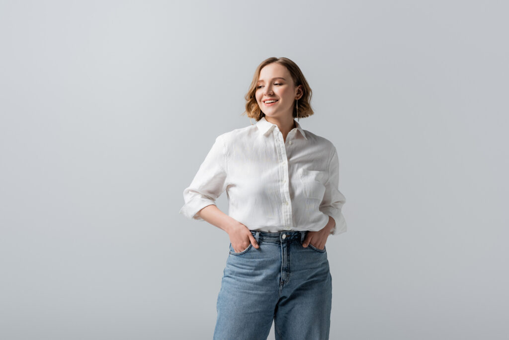 Photo of a woman wearing a white shirt and jeans against a gray background